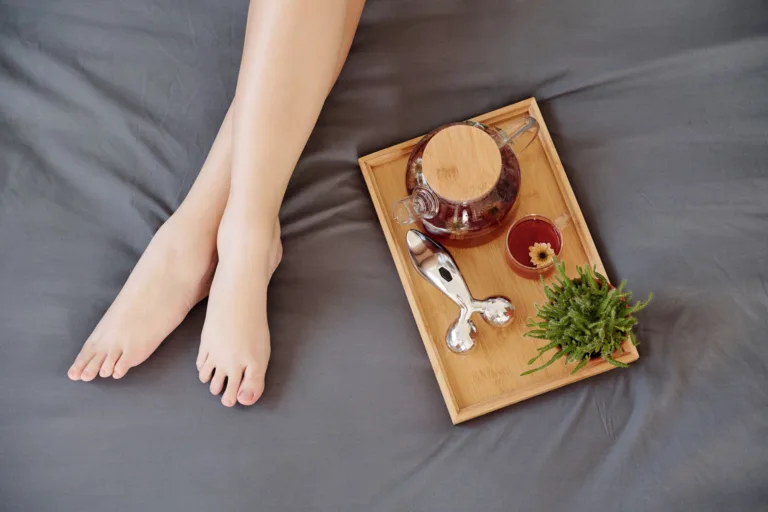 Relaxing tea tray beside crossed legs on bed.
